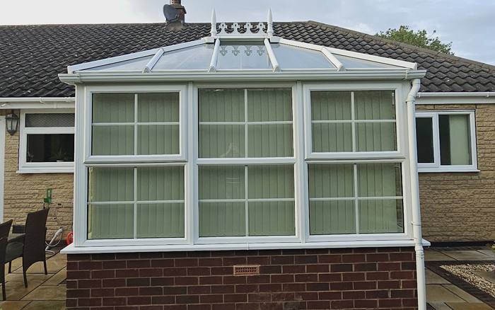 A conservatory glass roof and frames cleaned back to white
