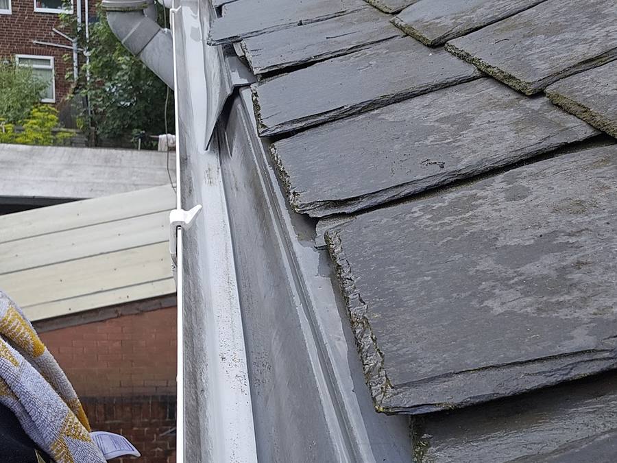 A gutter cleared and running clear along a slate roof