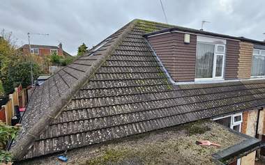 A hipped roof covered in moss and lichen before cleaning