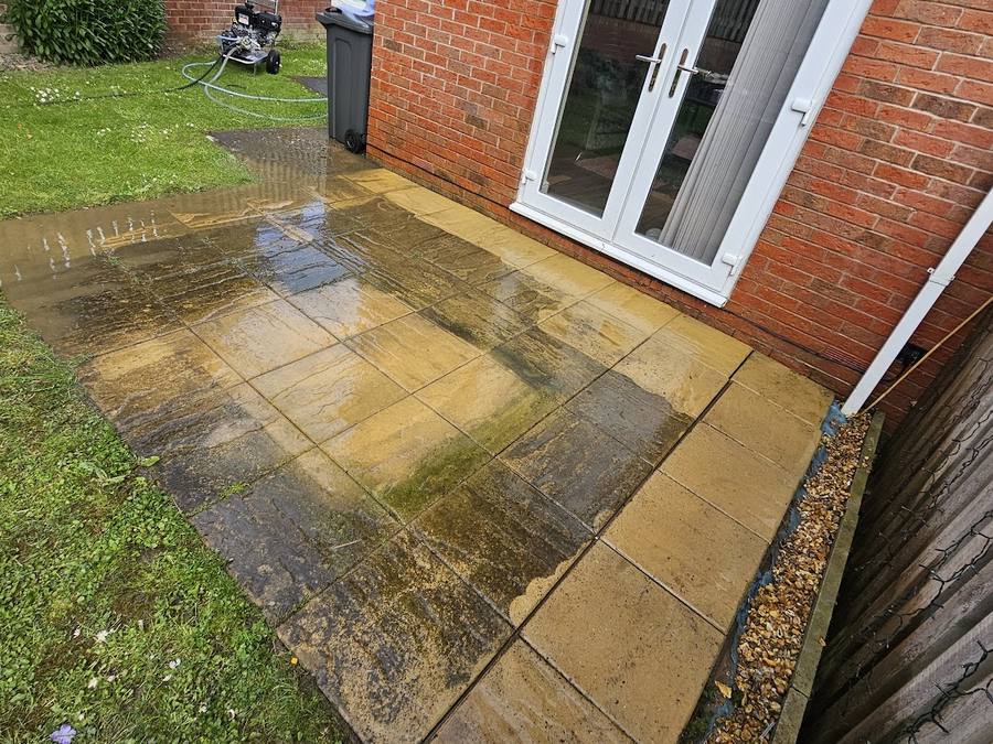 Indian sandstone patio part way through being pressure washed