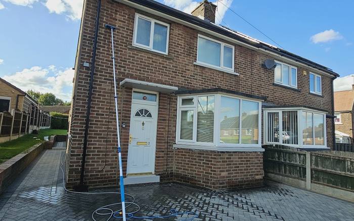 A house frontage being soft washed with a pole